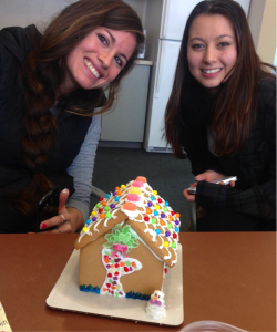 two students posing with gingerbread house