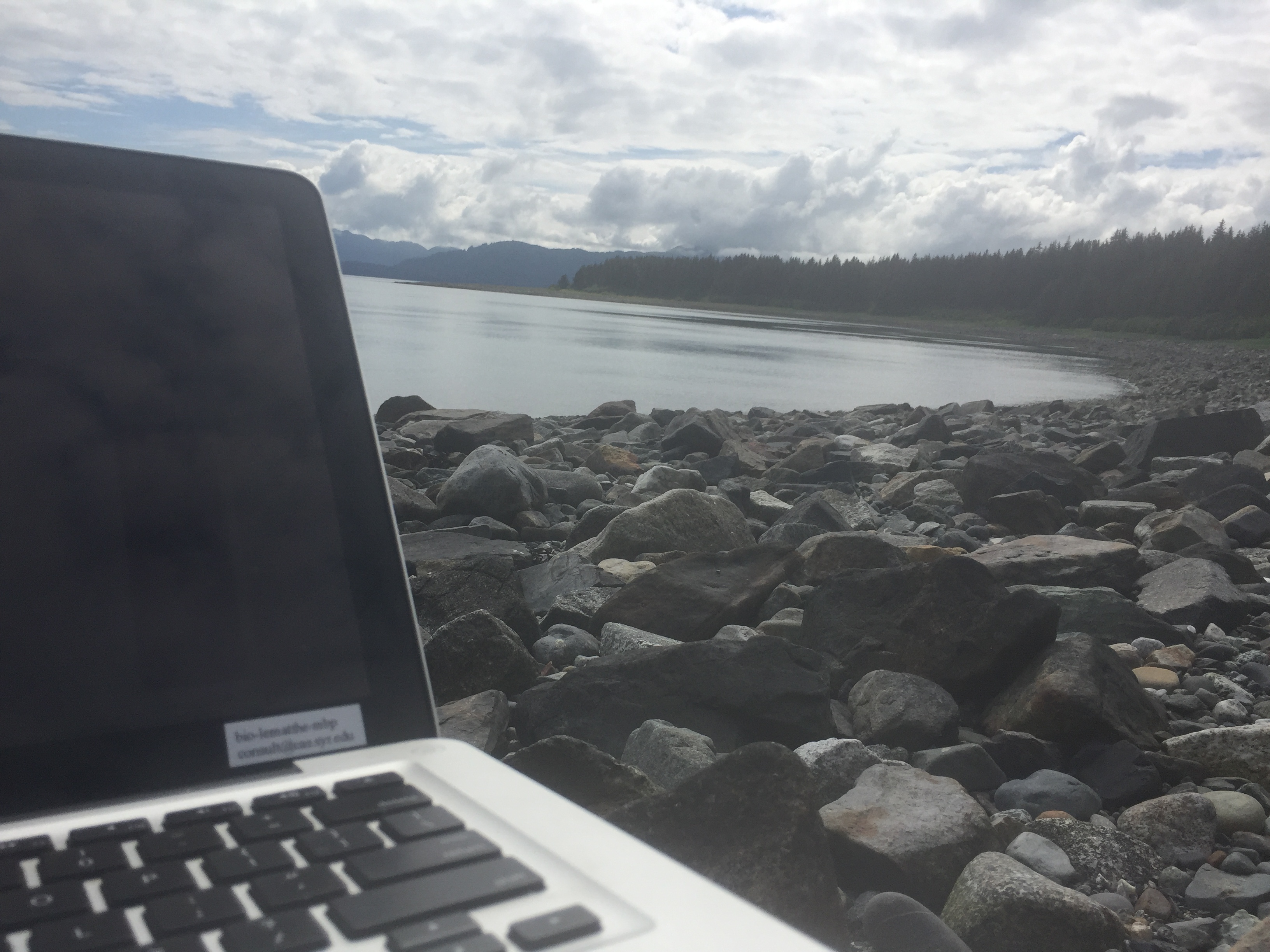 rocky beach shoreline with laptop in the foregrounf